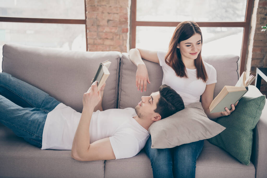 Portrait of his he her she nice attractive lovely focused cheerful cheery couple sitting lying on divan reading interesting book spending time pastime at modern industrial loft style brick interior - Photo, Image