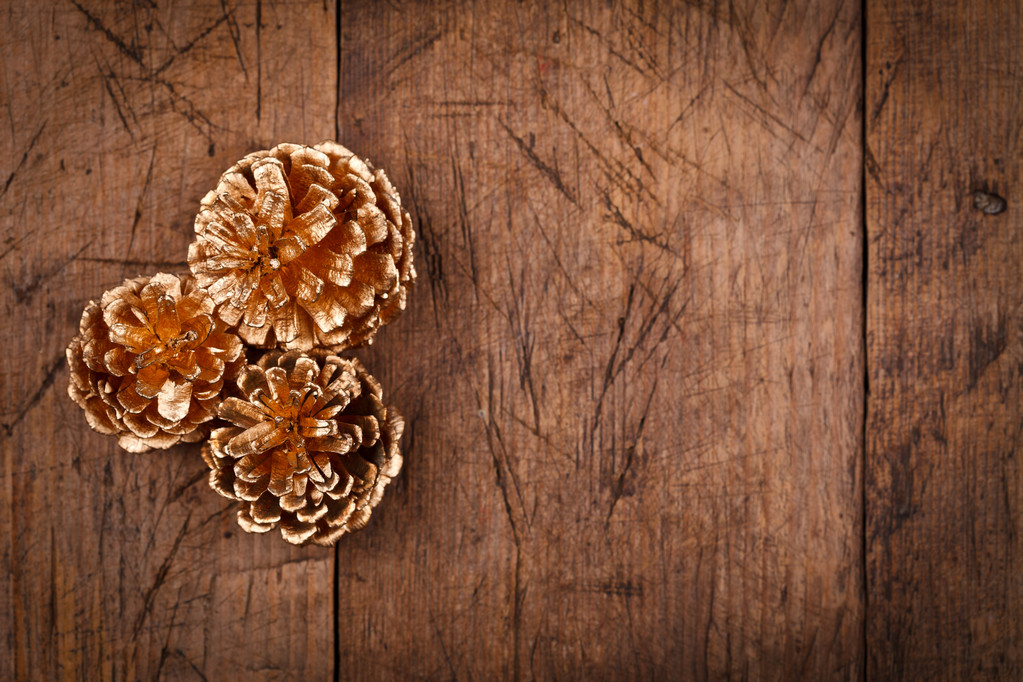Conos de pino dorado sobre mesa de madera
 - Foto, Imagen