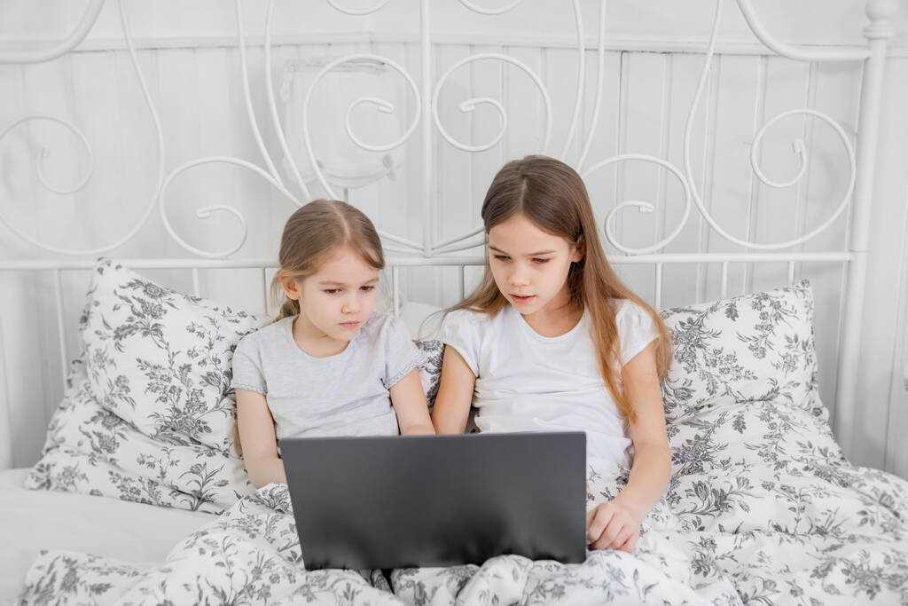 két testvér tanul a számítógép online otthoni ágy. - Fotó, kép