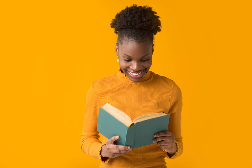 bela jovem mulher africana no fundo amarelo com um livro
 - Foto, Imagem