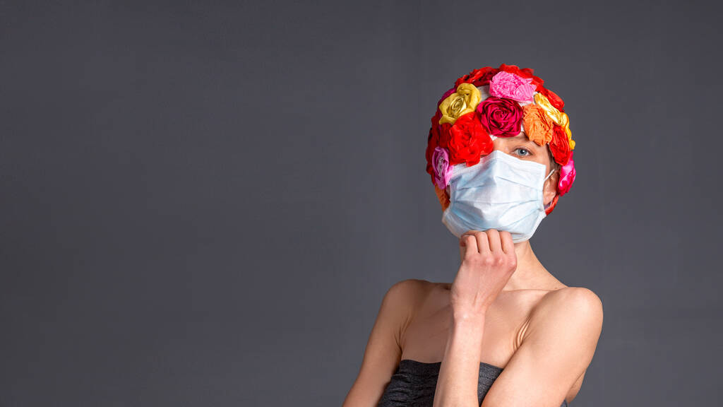 Donna con maschera medica indossando cappello fiore artificiale isolato su sfondo grigio. copia spazio
 - Foto, immagini