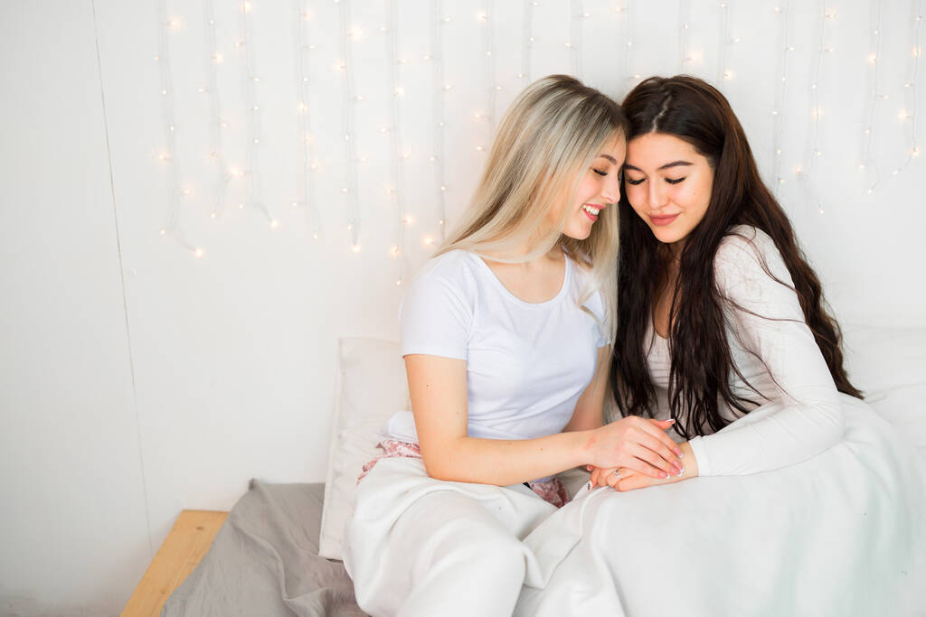 Две красивые молодые женщины на кровати
 - Фото, изображение