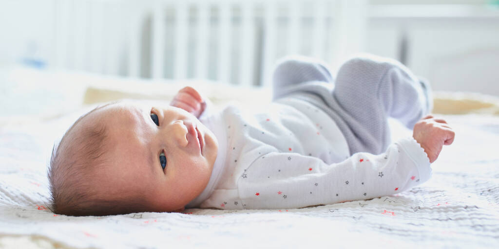Чарівна новонароджена дівчинка лежить на ліжку батьків вдома
 - Фото, зображення
