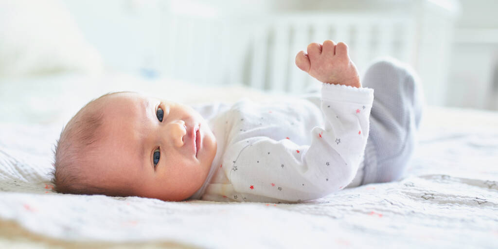 Adorable newborn baby girl lying on her parents' bed at home - Photo, Image
