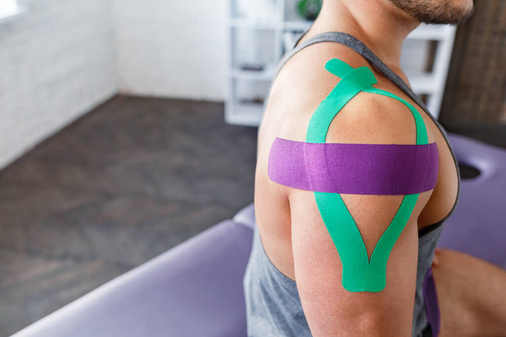 Kineziyoloji bandı. Hasta omzunda kineziyoloji bandı. Genç erkek atletin omuz tedavisi. Travma sonrası rehabilitasyon, spor fizyoterapisi, iyileşme konsepti - Fotoğraf, Görsel