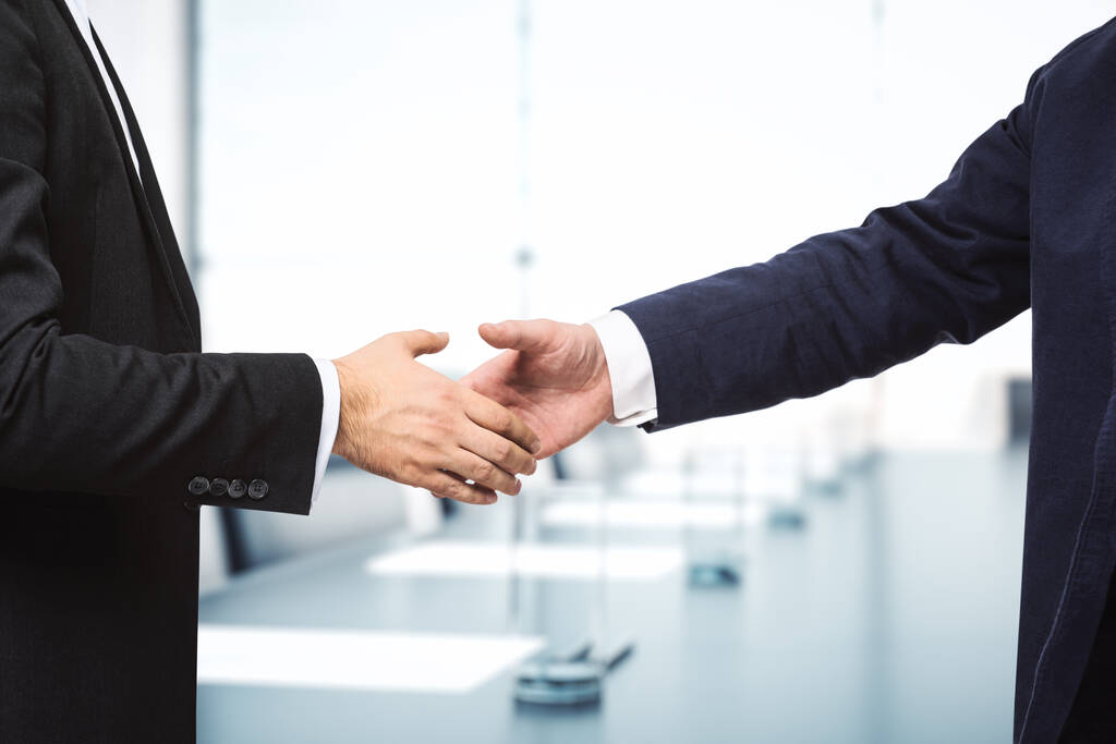 Twee zakenmannen schudden handen op de achtergrond van de zonnige vergaderzaal, deal concept, close-up - Foto, afbeelding