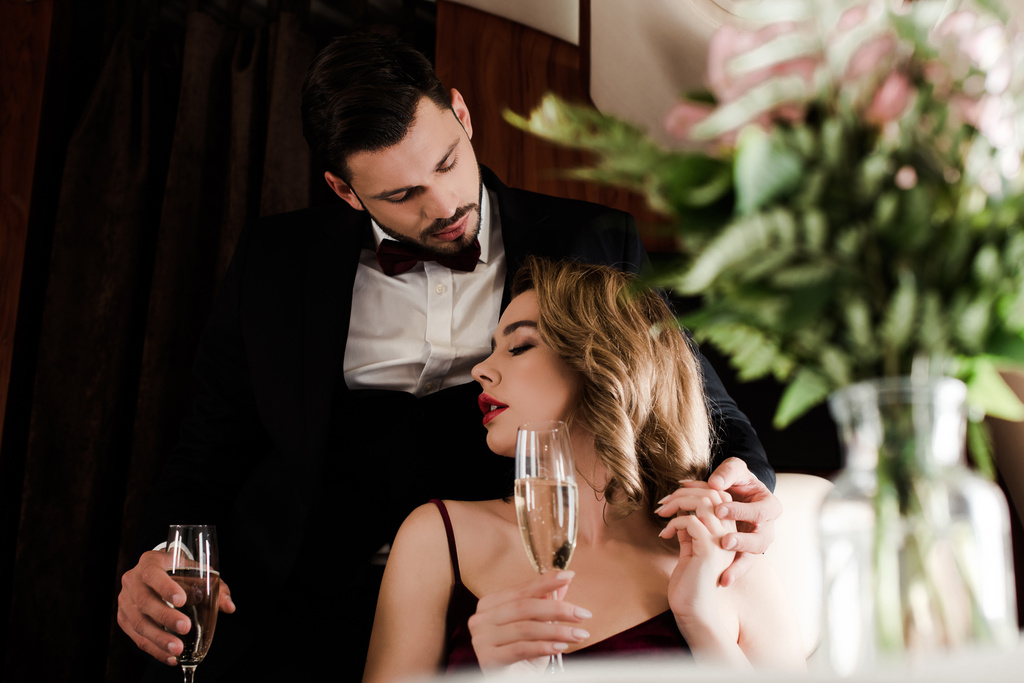 selektivní zaměření elegantního páru držícího sklenice šampaňského v letadle - Fotografie, Obrázek