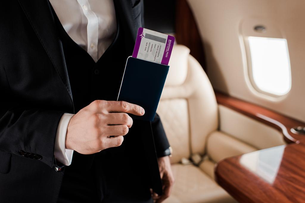 частичный вид элегантного человека с паспортом и авиабилетами в самолете
 - Фото, изображение