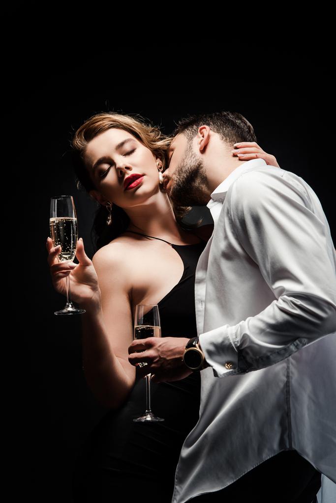 junger Mann in weißem Hemd ohne Knöpfe küsst sexy, elegantes Mädchen isoliert auf schwarz - Foto, Bild