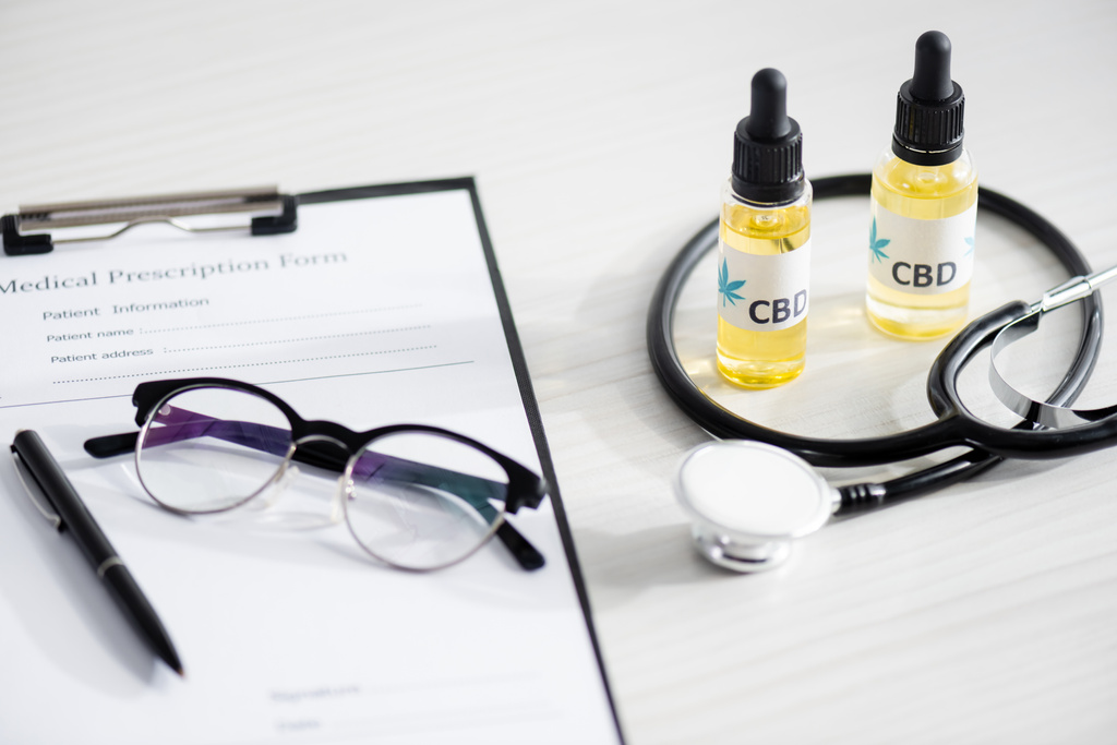 selective focus of bottles with cbd lettering near stethoscope, glasses and clipboard with medical prescription form  - Photo, Image