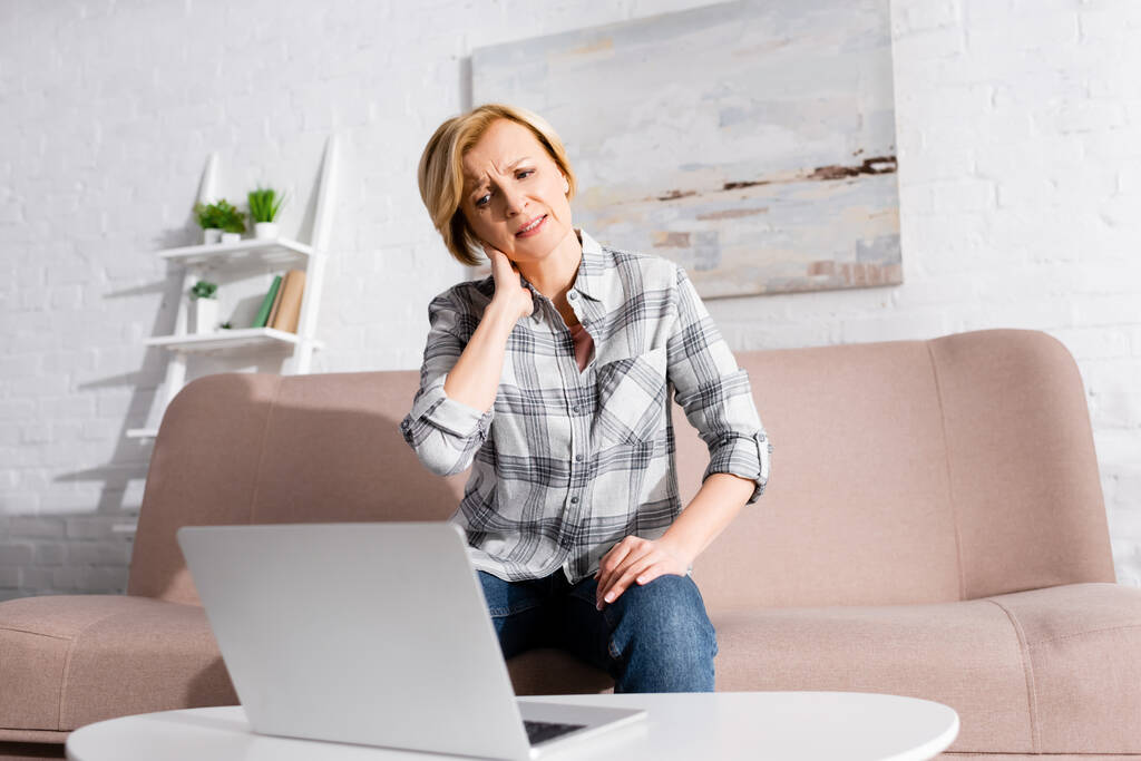 volwassen freelancer die lijden aan nekpijn en kijken naar laptop  - Foto, afbeelding
