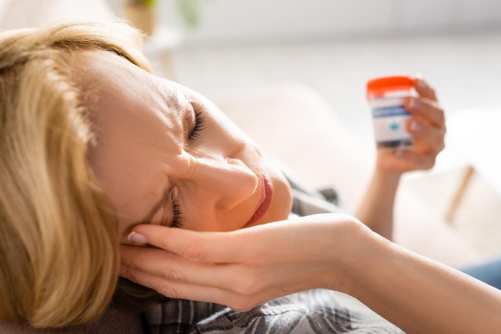 szelektív fókusz érett nő migrén gazdaság palack orvosi kannabisz betűkkel  - Fotó, kép