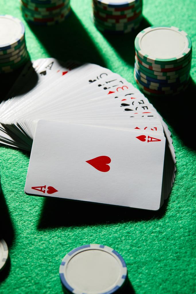 Vue grand angle du paquet de cartes avec des jetons de casino sur fond vert
 - Photo, image