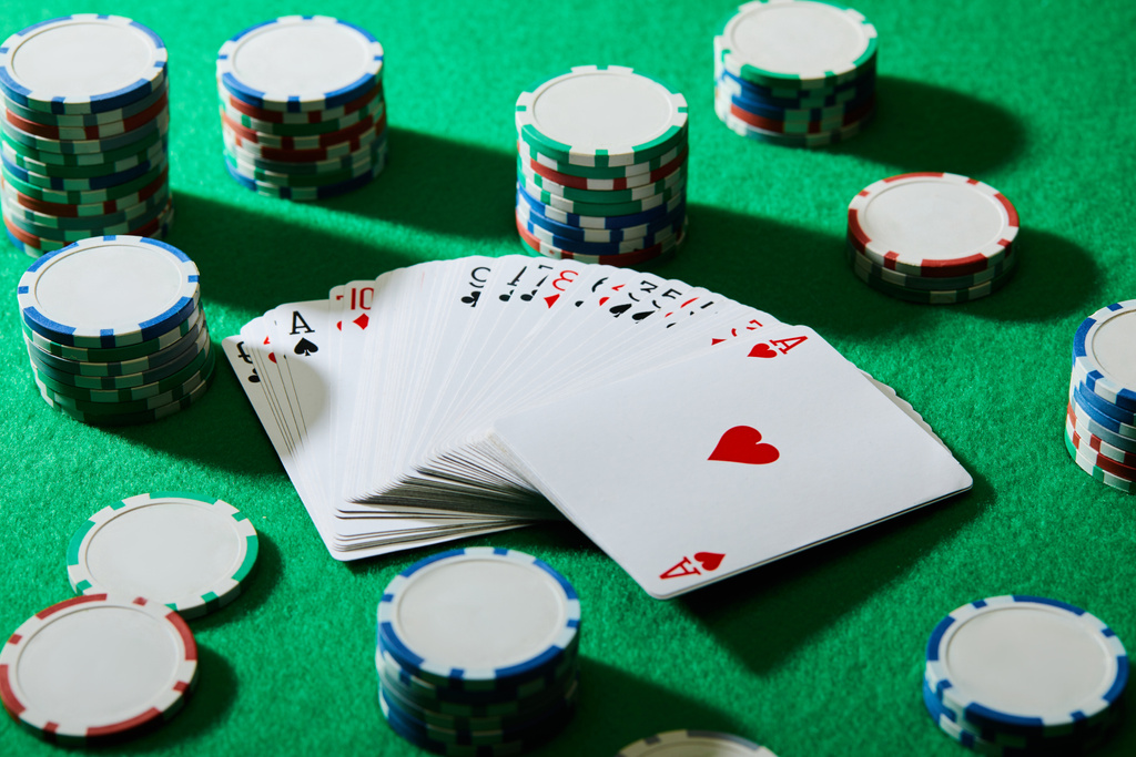 Hohe Winkelansicht des Kartenspiels mit Casino-Chips auf Grün - Foto, Bild