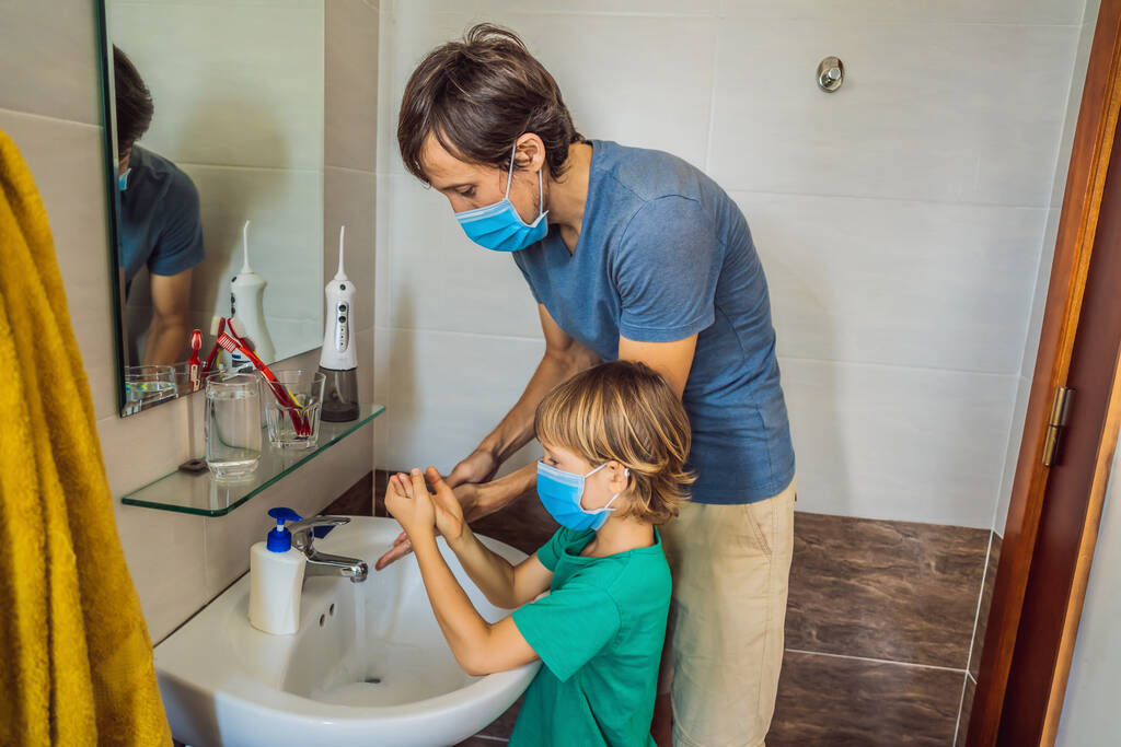 Papá le enseña a su hijo a lavarse bien las manos. Papá e hijo con máscaras médicas por coronovirus. Epidemia. Quédate en casa. Lávate las manos
 - Foto, Imagen