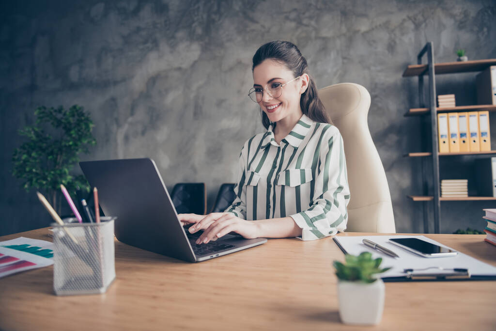 Positiivinen muotokuva iloinen freelancer asianajaja tyttö sit desk työ kannettava tietokone kirjoittaa online-viestin start-up sijoittajat käyttävät raidallinen valkoinen paita työasemalla
 - Valokuva, kuva