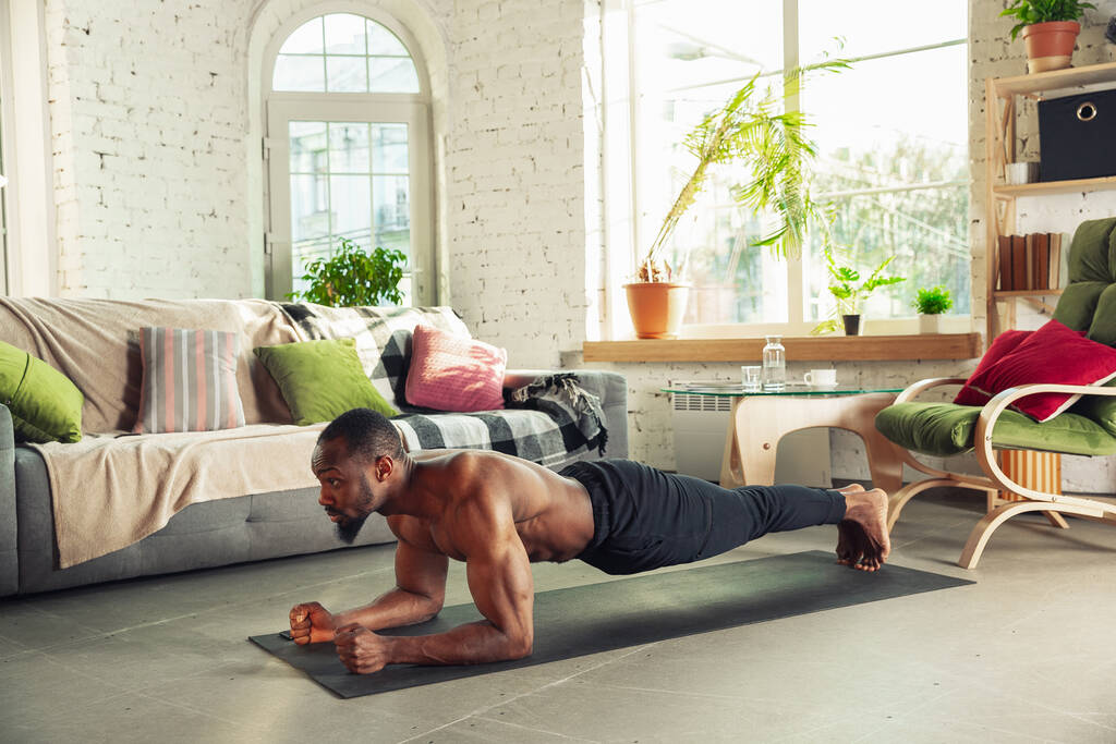 Hombre afroamericano joven que enseña en casa cursos en línea de fitness, aeróbico, estilo de vida deportivo mientras está en cuarentena
 - Foto, imagen