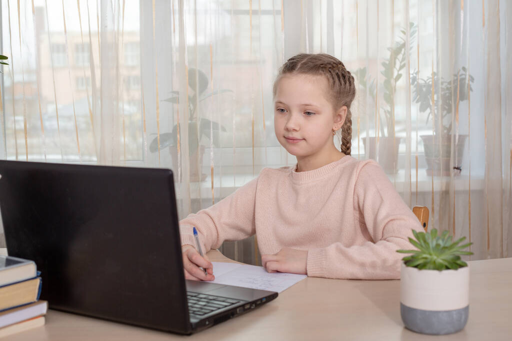Una colegiala que estudia en casa. Chica joven usando el ordenador portátil en casa. Educación a distancia, educación en el hogar. Concepto de autoaislamiento - Imagen
 - Foto, imagen