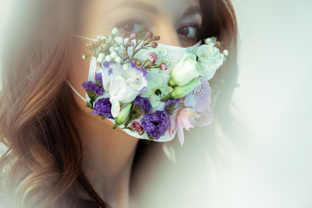 enfoque selectivo de la mujer atractiva en la máscara facial floral mirando a la cámara en blanco
 - Foto, Imagen