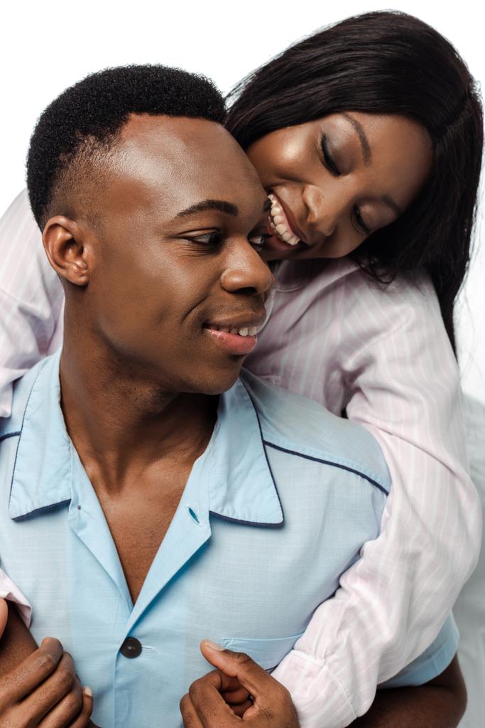 幸せなアフリカ系アメリカ人のカップルが白で隔離されたパジャマに身を包み - 写真・画像