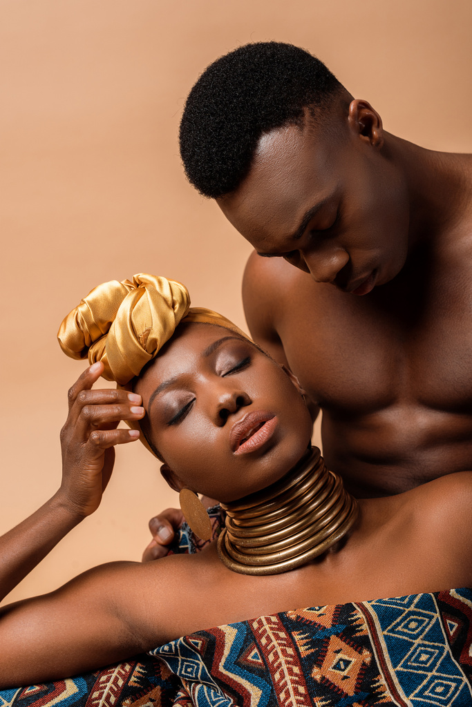 sexy desnudo tribal afro mujer cubierto en manta posando cerca de hombre aislado en beige
 - Foto, imagen