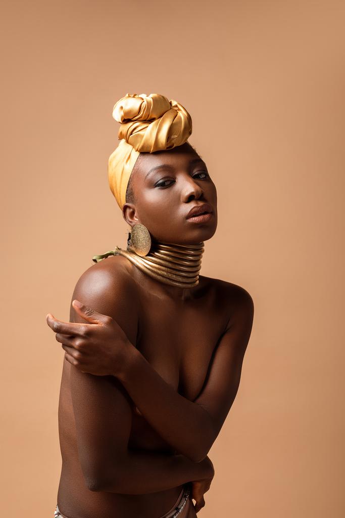 sexy naakt tribal afro vrouw poseren geïsoleerd op beige - Foto, afbeelding