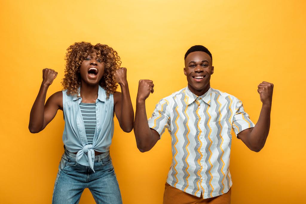 ευτυχισμένο ζευγάρι Αφροαμερικανών που δείχνει ναι χειρονομία σε κίτρινο πολύχρωμο φόντο - Φωτογραφία, εικόνα