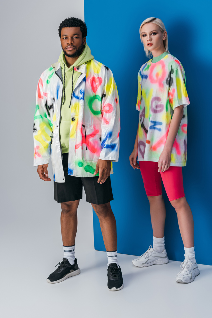 pareja interracial de moda posando en mirada futurista colorido en gris y azul
 - Foto, imagen
