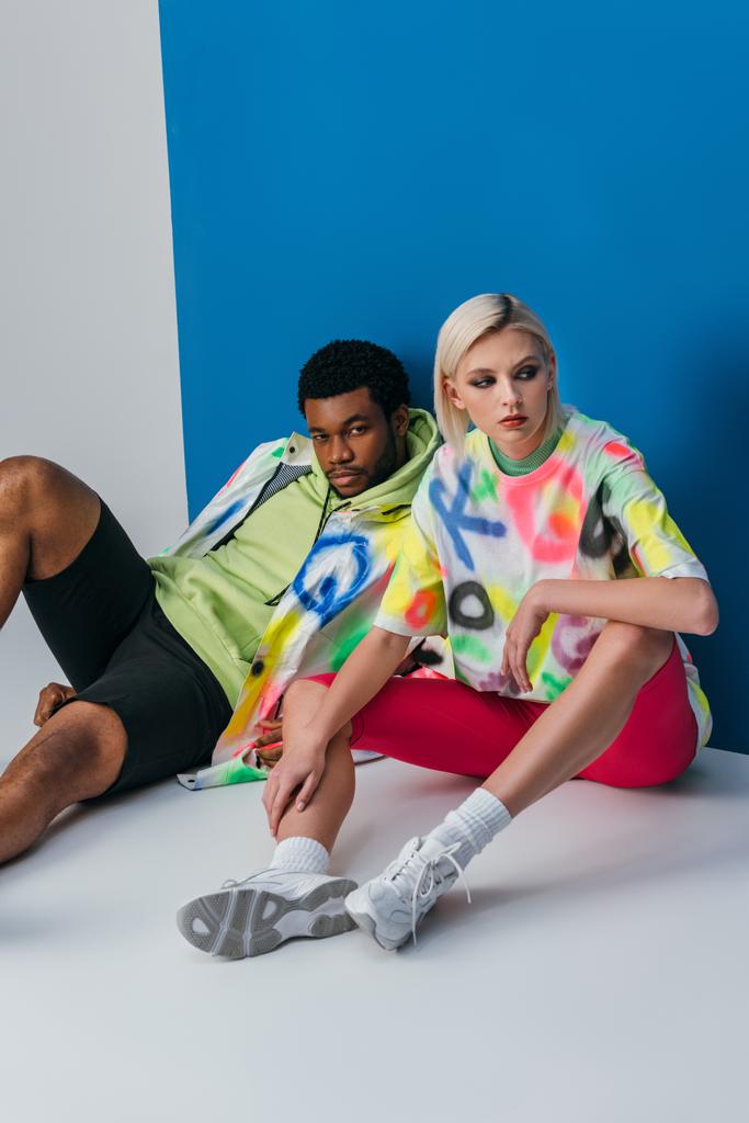 multikulturális pár pózol színes futurisztikus megjelenés szürke és kék - Fotó, kép
