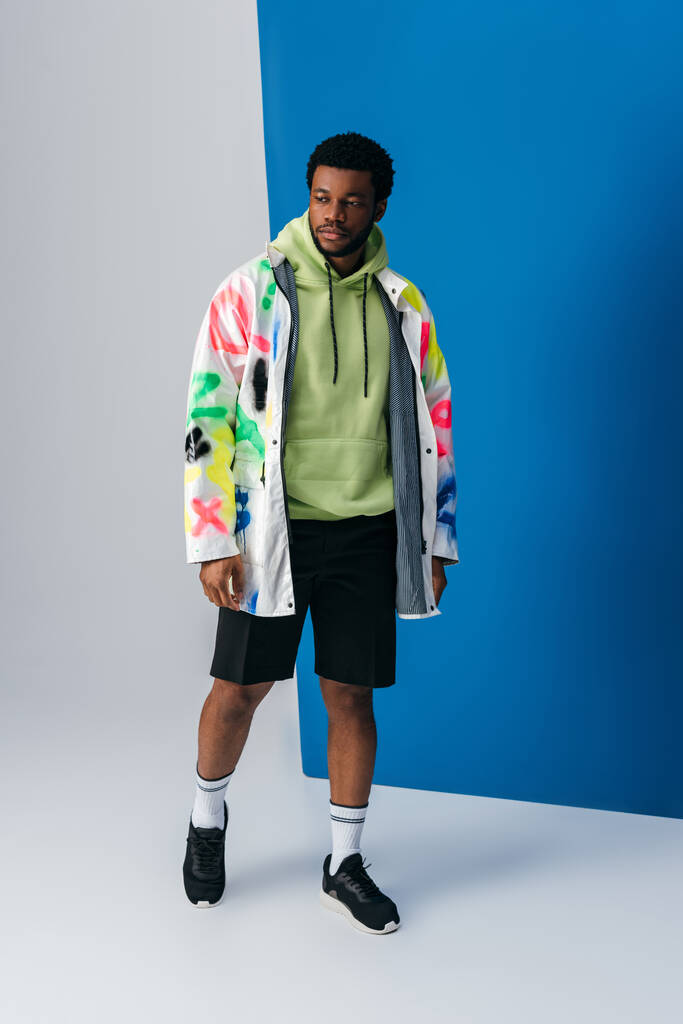 handsome african american man posing in colorful futuristic clothes on grey and blue - Photo, Image