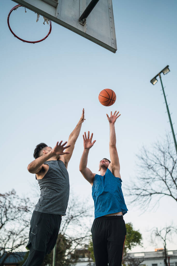 Πορτρέτο δύο νεαρών φίλων που παίζουν μπάσκετ και διασκεδάζουν στο γήπεδο. Αθλητική έννοια. - Φωτογραφία, εικόνα