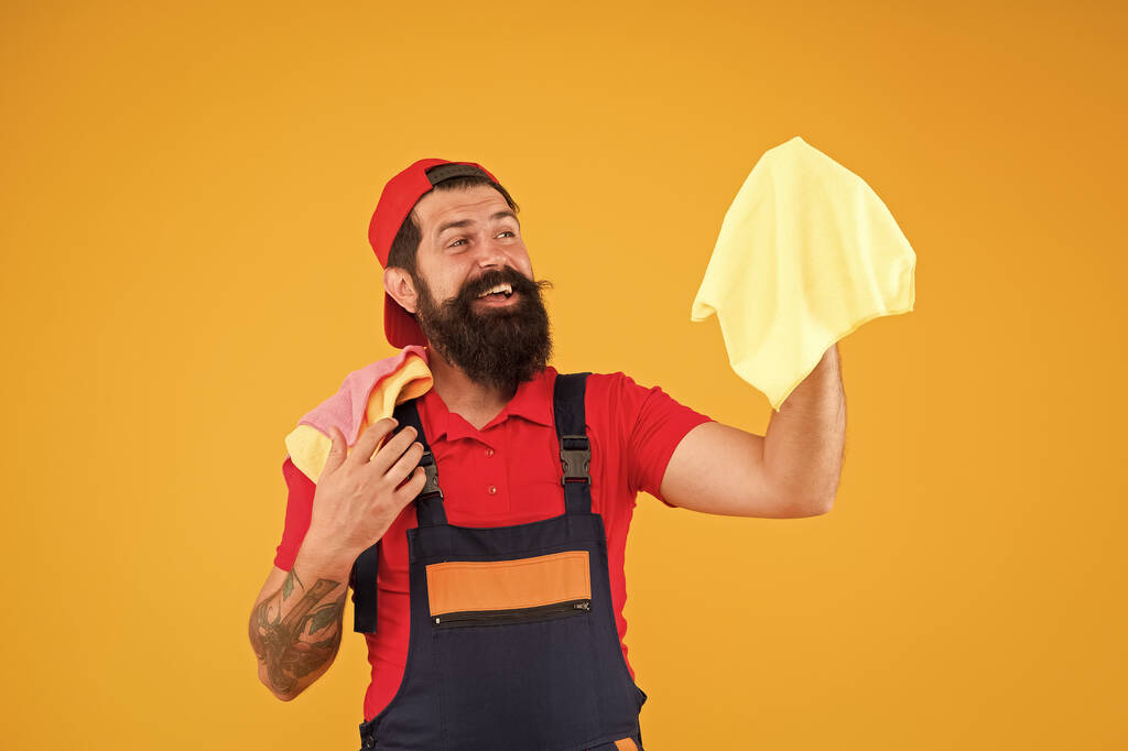 家をきれいに見えると新鮮な感じを取得するために迅速に動作します。男残酷な陽気なひげを生やした労働者のほこりのラグを拭く。掃除用品のコンセプト。簡単な洗浄のヒント。男は一片の布で働く - 写真・画像
