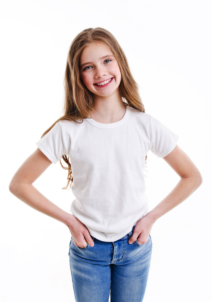 Portrét rozkošné usměvavé holčičky předpuberťačky v džínách a bílém tričku izolované na růžovém pozadí - Fotografie, Obrázek