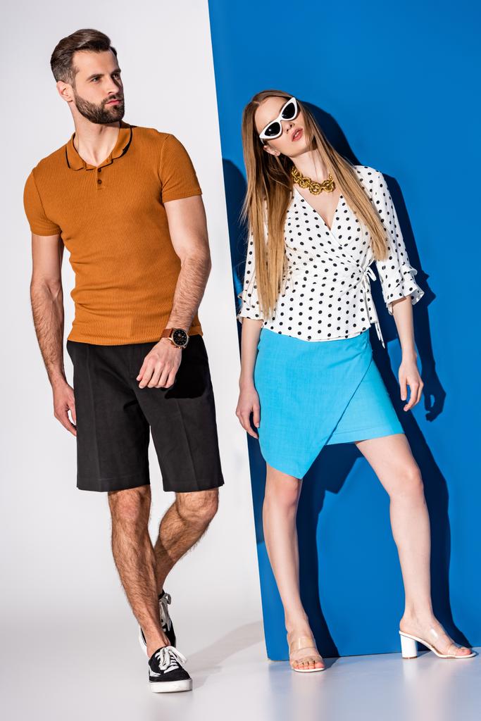 beautiful fashionable couple posing in summer clothes and sunglasses on grey and blue - Photo, Image