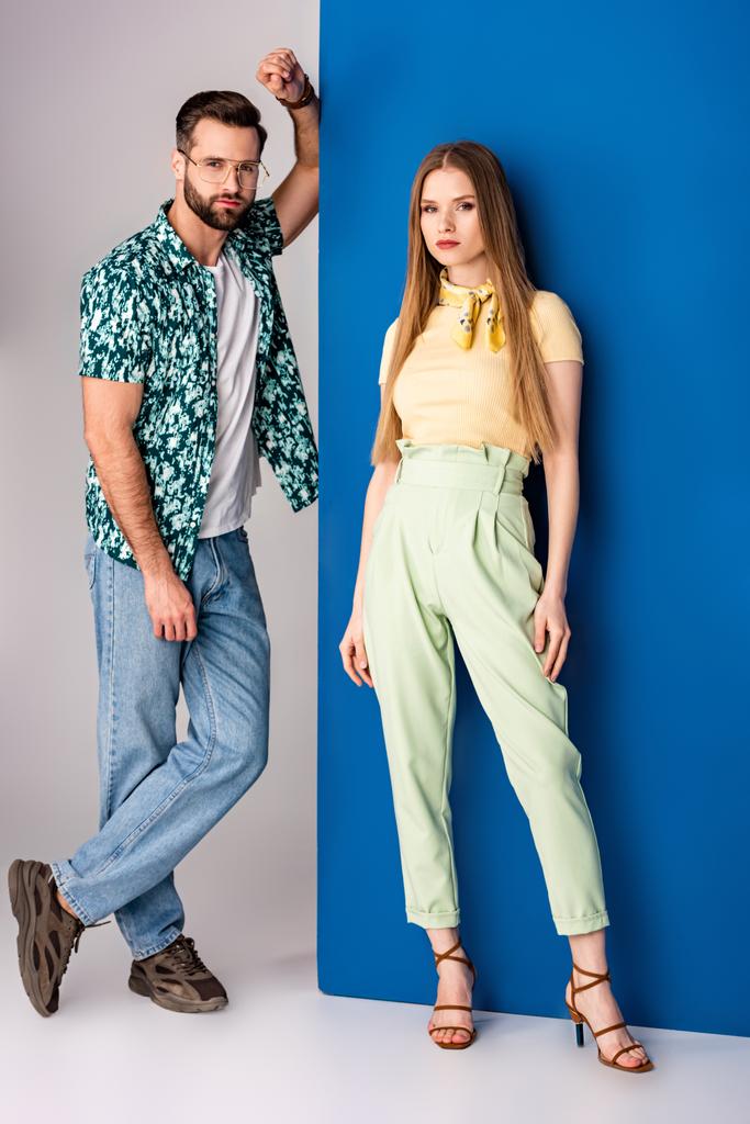stylový mladý pár pózující v letních šatech na šedé a modré  - Fotografie, Obrázek