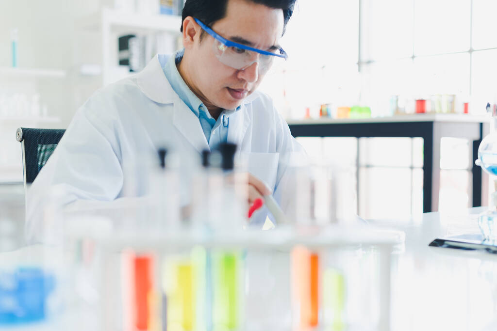 Cientistas asiáticos estão preparando produtos químicos para testes e análises em laboratório. Os cientistas limpam copos e camisas brancas. Conceito de Ciência e Química
 - Foto, Imagem