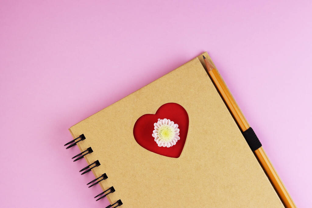un corazón de amor en un bloc de notas con un bolígrafo en una mesa de madera azul. portátil marrón con un corazón rojo
 - Foto, Imagen