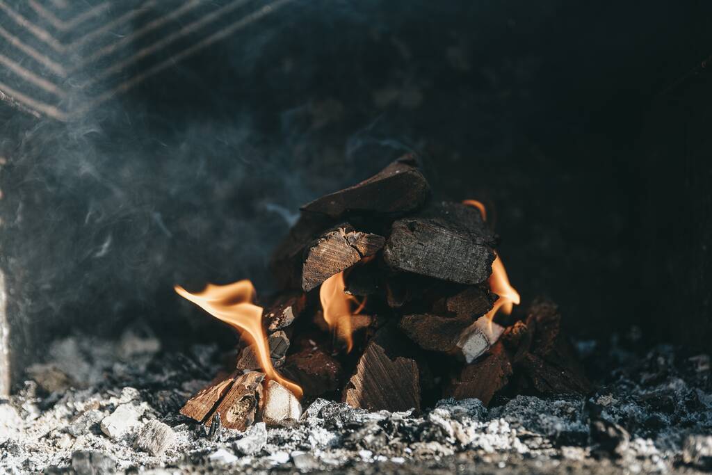 Eine Nahaufnahme von brennendem Brennholz auf verschwommenem Hintergrund - Foto, Bild