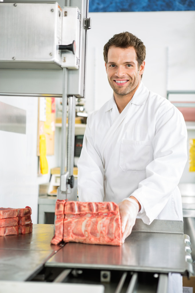 Boucher tranchant la viande sur scie à ruban
 - Photo, image