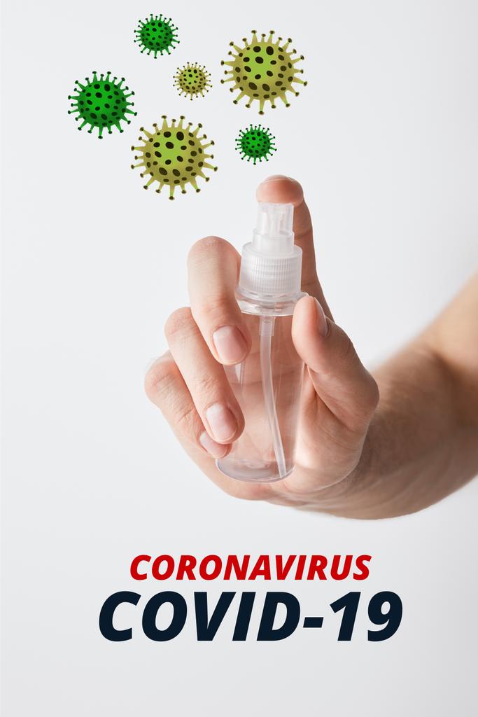 vista recortada del hombre que sostiene el desinfectante de la mano en botella del aerosol aislado en blanco, ilustración del coronavirus
 - Foto, Imagen