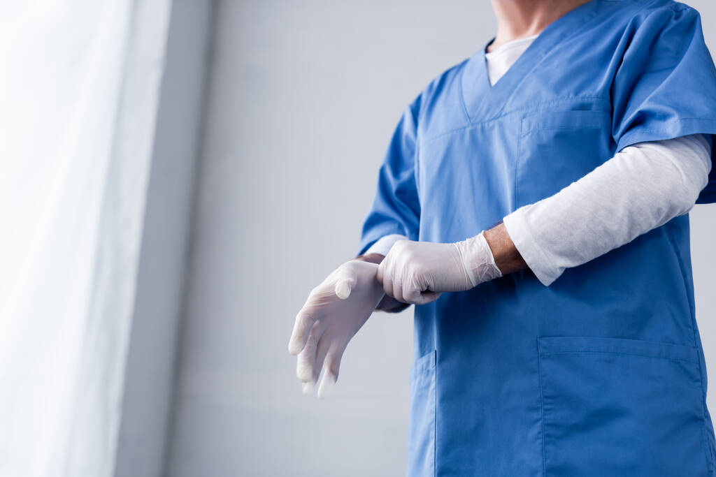 Beyazın üstüne lateks eldiven takan olgun bir doktor görüntüsü.  - Fotoğraf, Görsel
