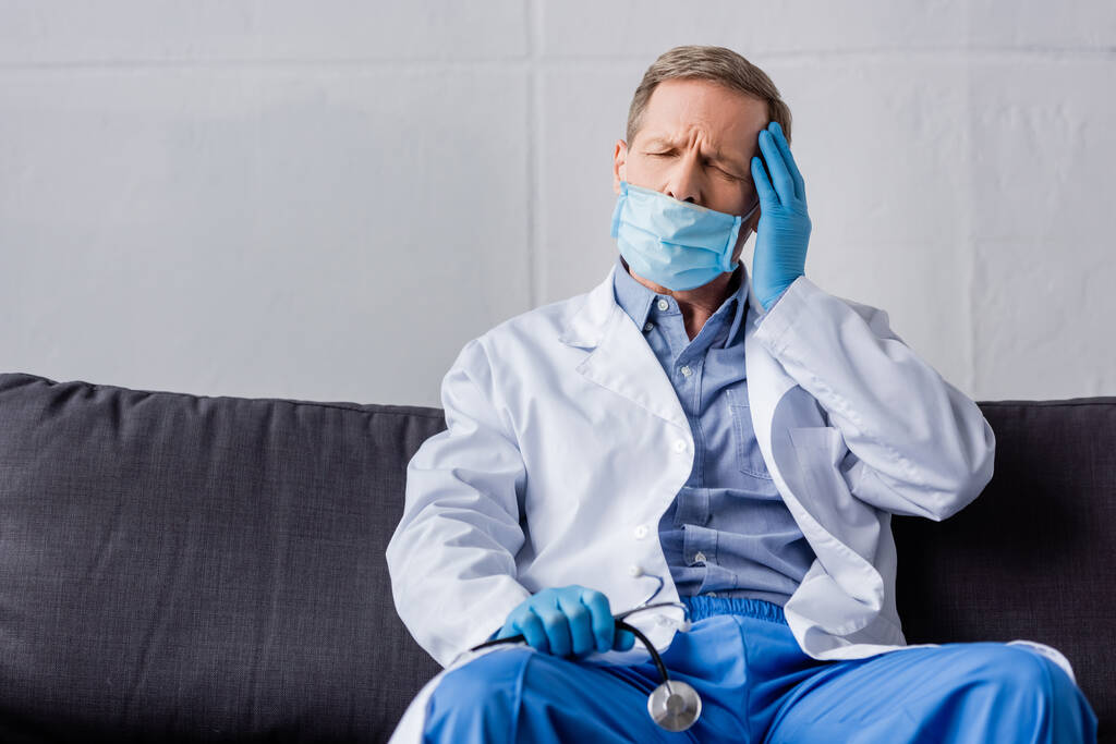 väsynyt kypsä lääkäri suljetuin silmin istuu sohvalla ja tilalla stetoskooppi
  - Valokuva, kuva
