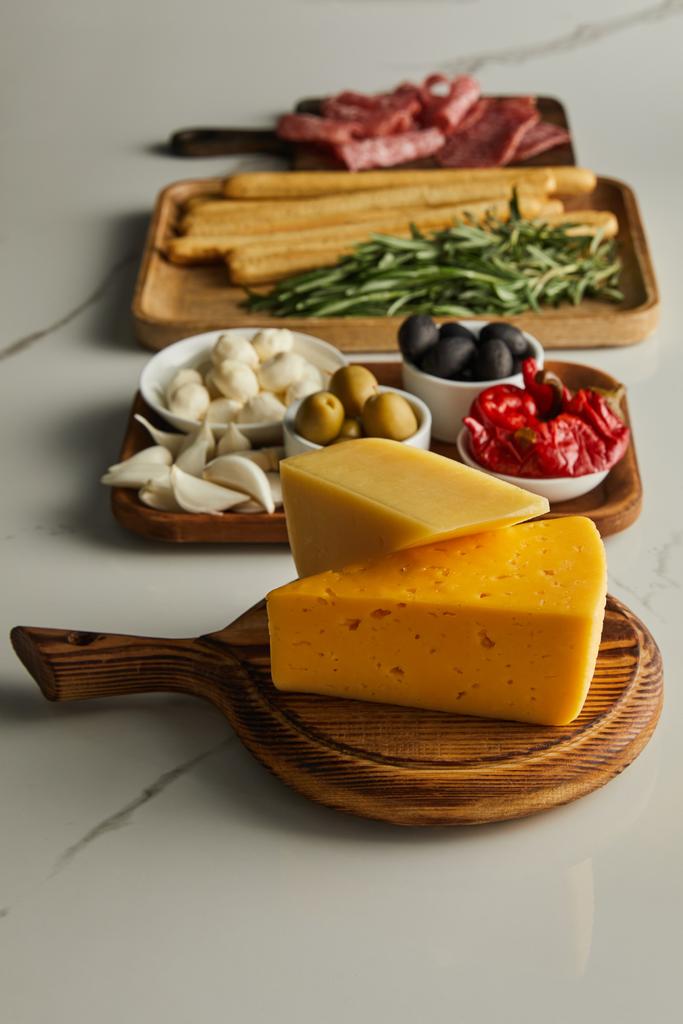 Selektive Fokussierung der Tafeln mit Käse und Antipasto-Zutaten auf weißem Hintergrund - Foto, Bild