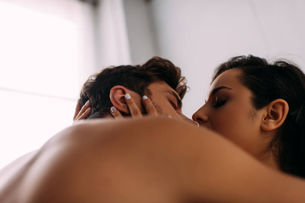 Selektywne skupienie pary z zamkniętymi oczami całujących się i przytulających w sypialni - Zdjęcie, obraz