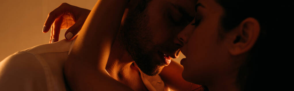 Femme passionnée embrassant homme d'affaires avec les yeux fermés dans la chambre, vue panoramique
 - Photo, image