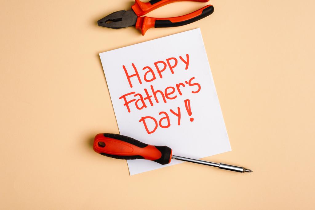 top view of screwdriver, pliers and greeting card with lettering happy fathers day on beige background - Photo, Image