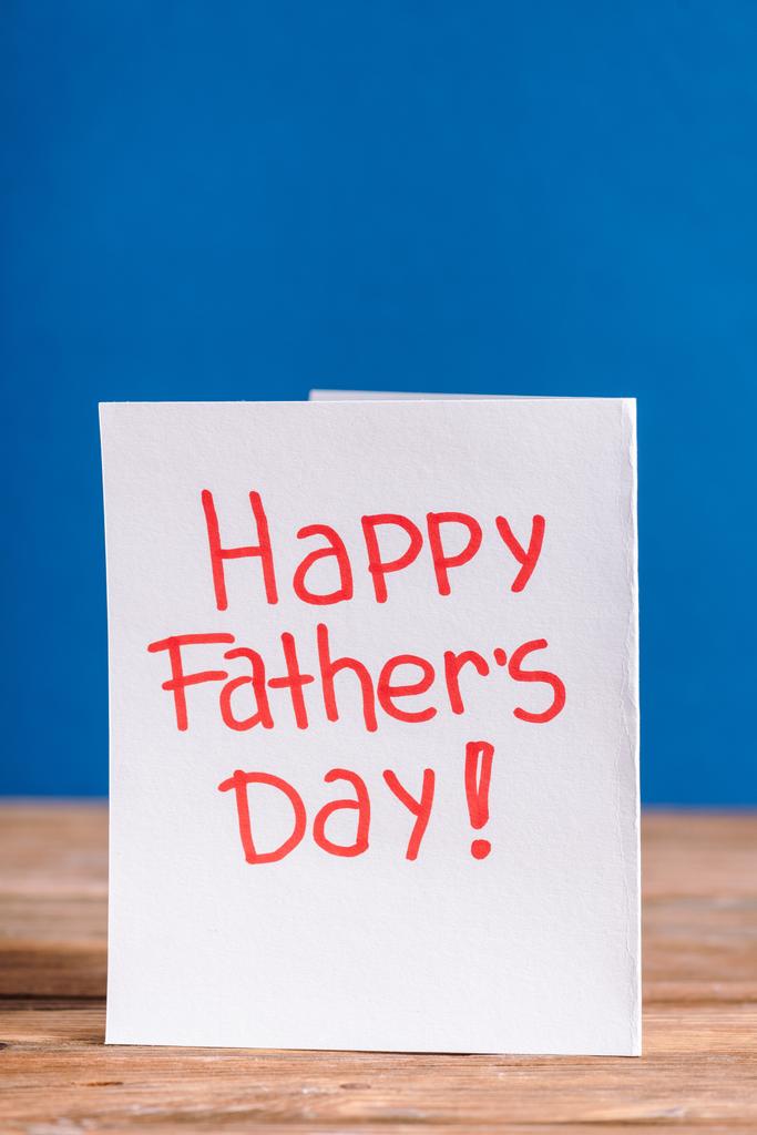 Λευκή ευχετήρια κάρτα με κόκκινα γράμματα χαρούμενη ημέρα πατεράδων απομονωμένη στο μπλε - Φωτογραφία, εικόνα
