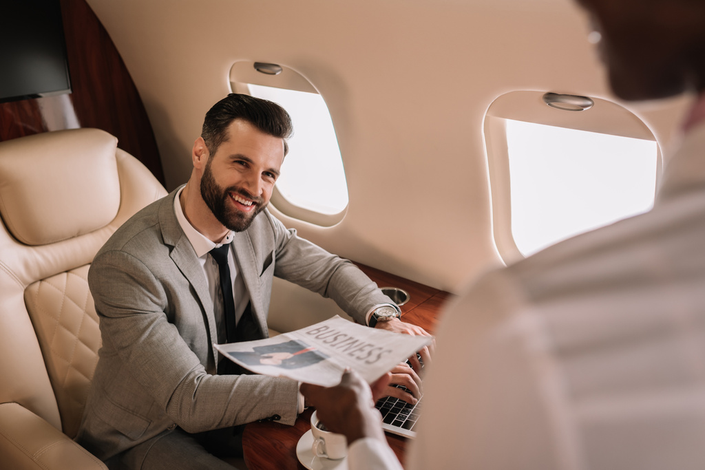 valikoiva painopiste komea liikemies katselee afrikkalainen amerikkalainen lentoemäntä antaa hänelle sanomalehti
 - Valokuva, kuva