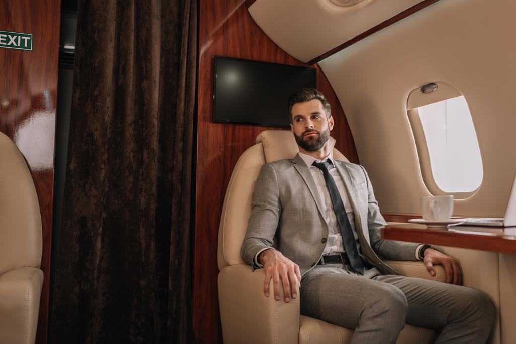bel homme d'affaires voyageant en avion privé tout en étant assis près de la table avec une tasse de café
 - Photo, image