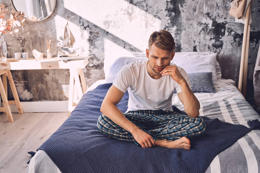 Negative Freude junger Mann sitzt auf dem Bett - Foto, Bild
